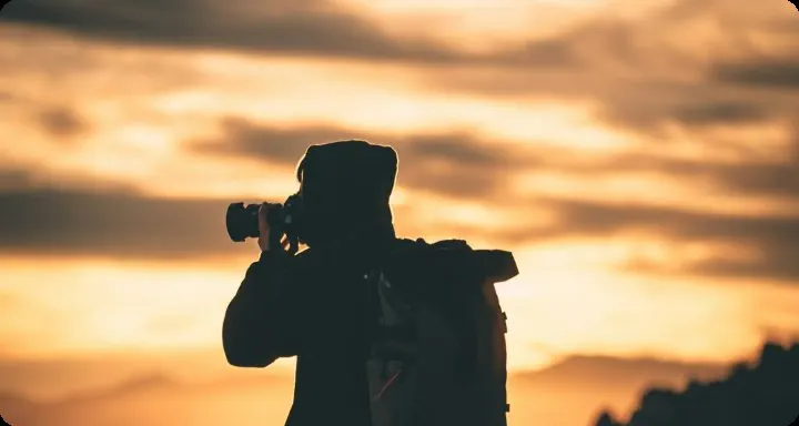 Wildlife photographer silhouetted against golden storm clouds