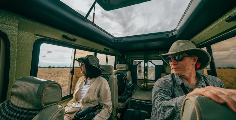 Travelers watching wildlife from inside a safari vehicle with pop-up roof