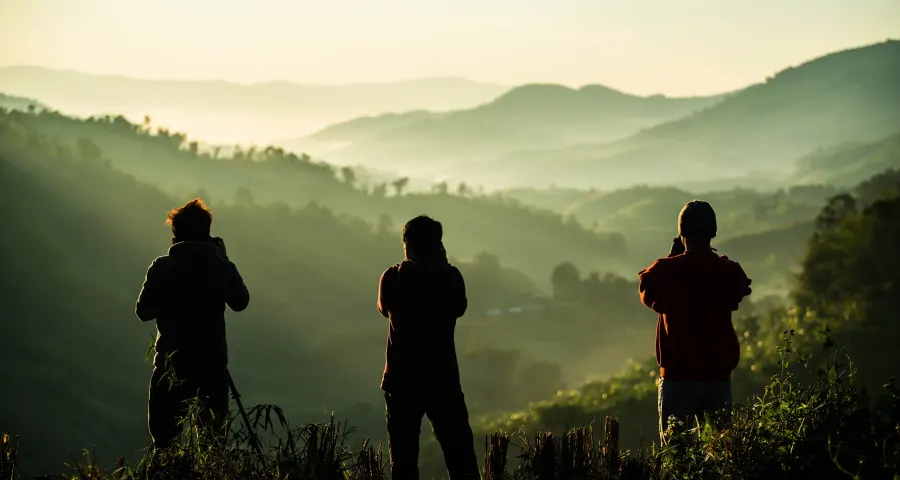 Photographer silhouetted with tripod against a pink and orange sunset