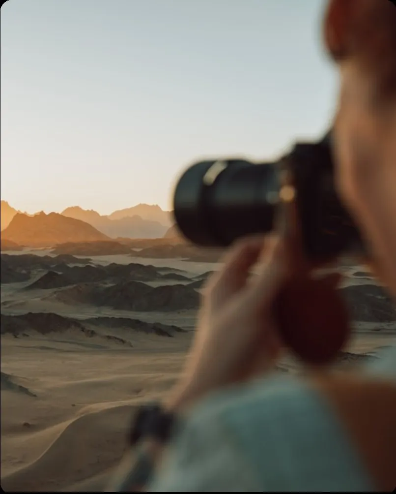 Close view of a telephoto lens with desert dunes beyond
