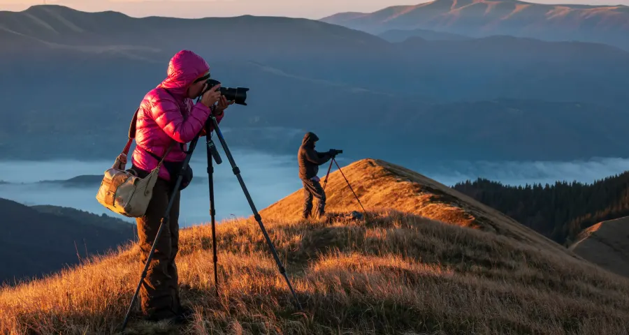 Photographer with tripod working from a rocky outcrop in soft mist
