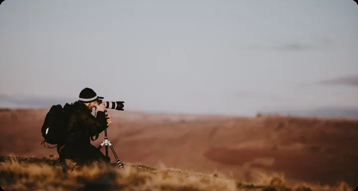 Photographer crouching with telephoto lens in arid hills