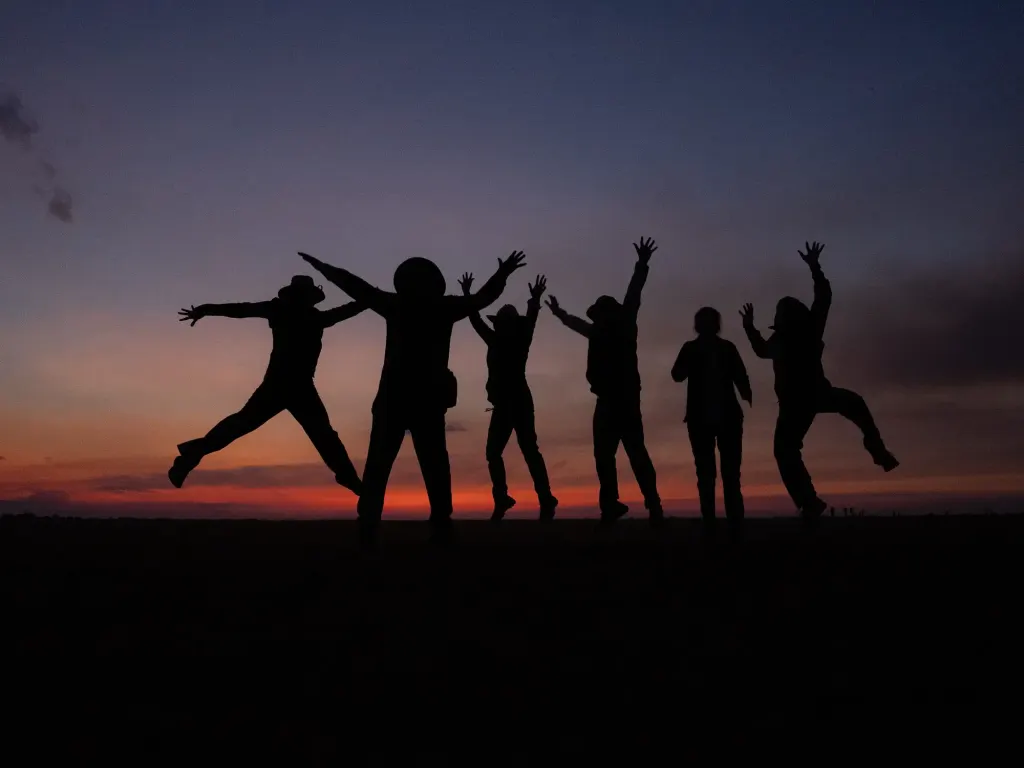 Travelers jumping against the sunset sky