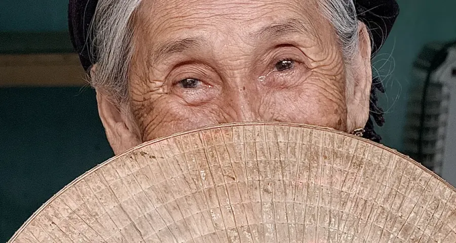 Elder in traditional dress holding a palm-leaf fan