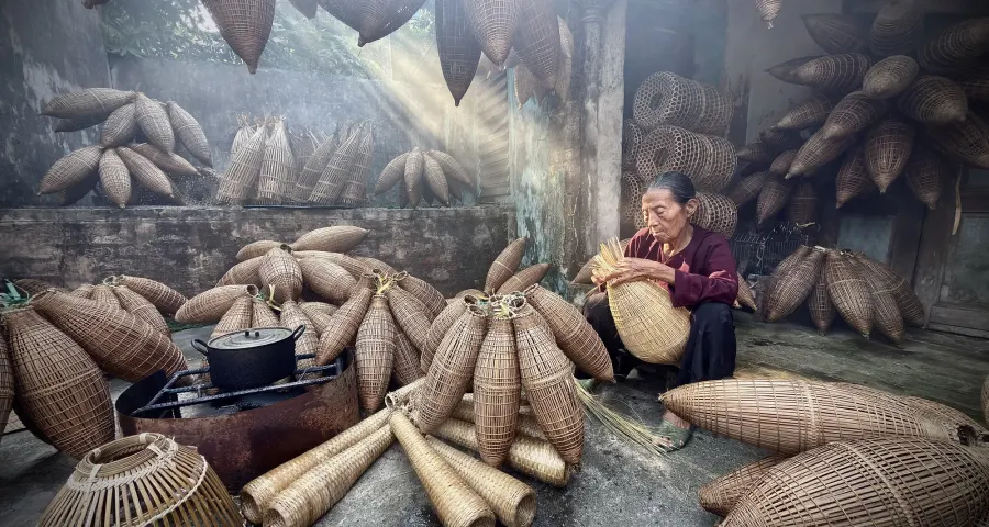 Artisan weaving fish traps in a smoke-lit workshop