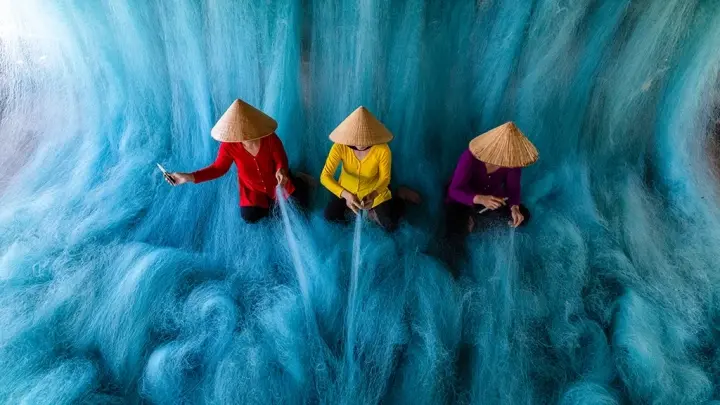 Workers repairing turquoise fishing nets